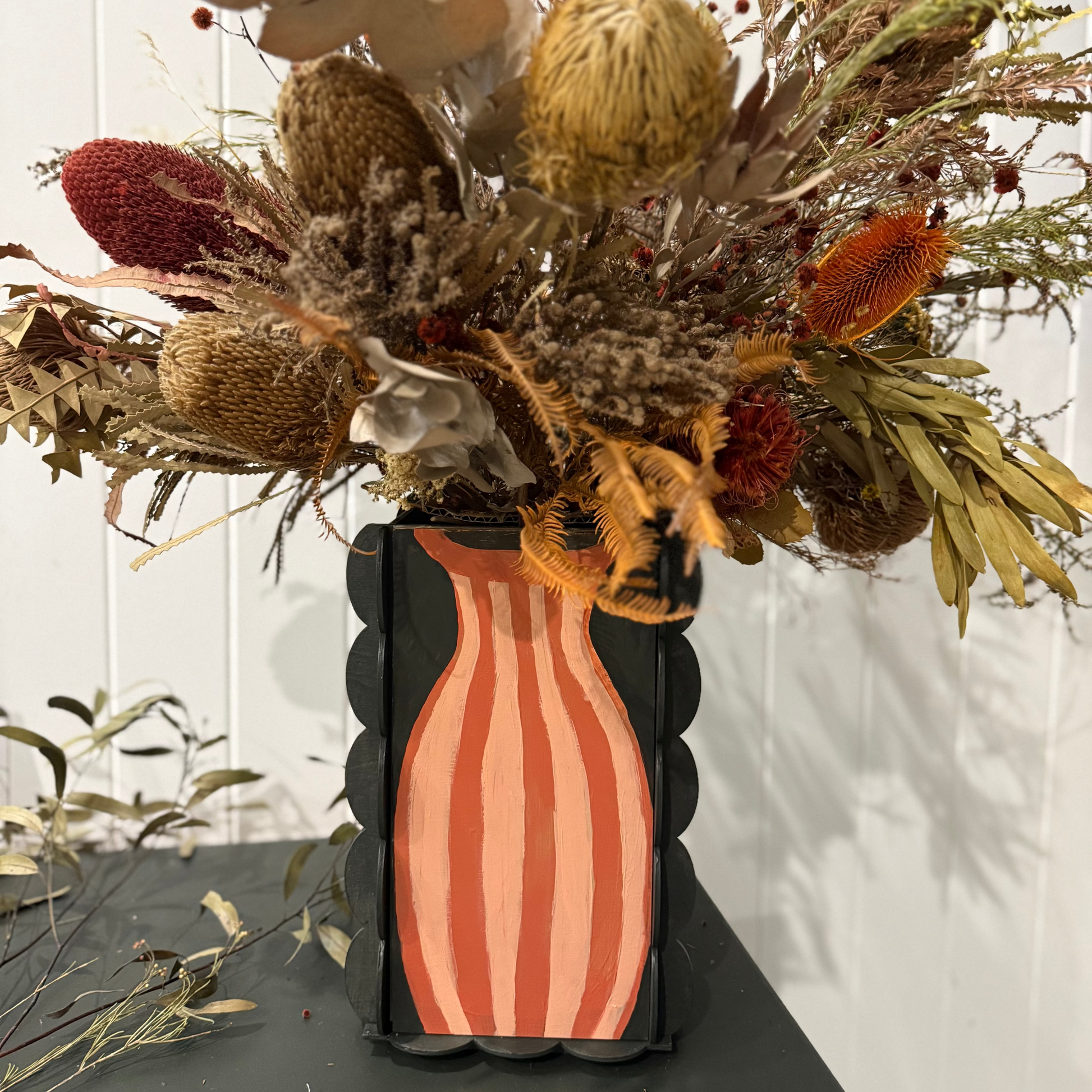 Decorative vase with striped pattern holding a bouquet of dried flowers on a white background